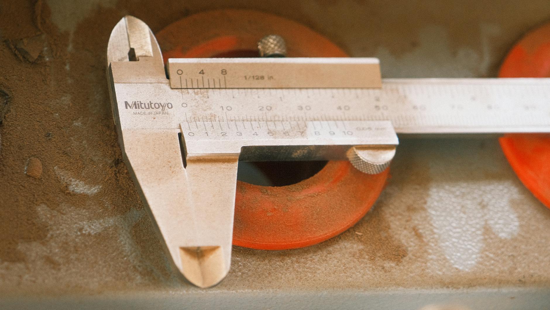 A precision vernier caliper measuring tool on a dusty industrial surface